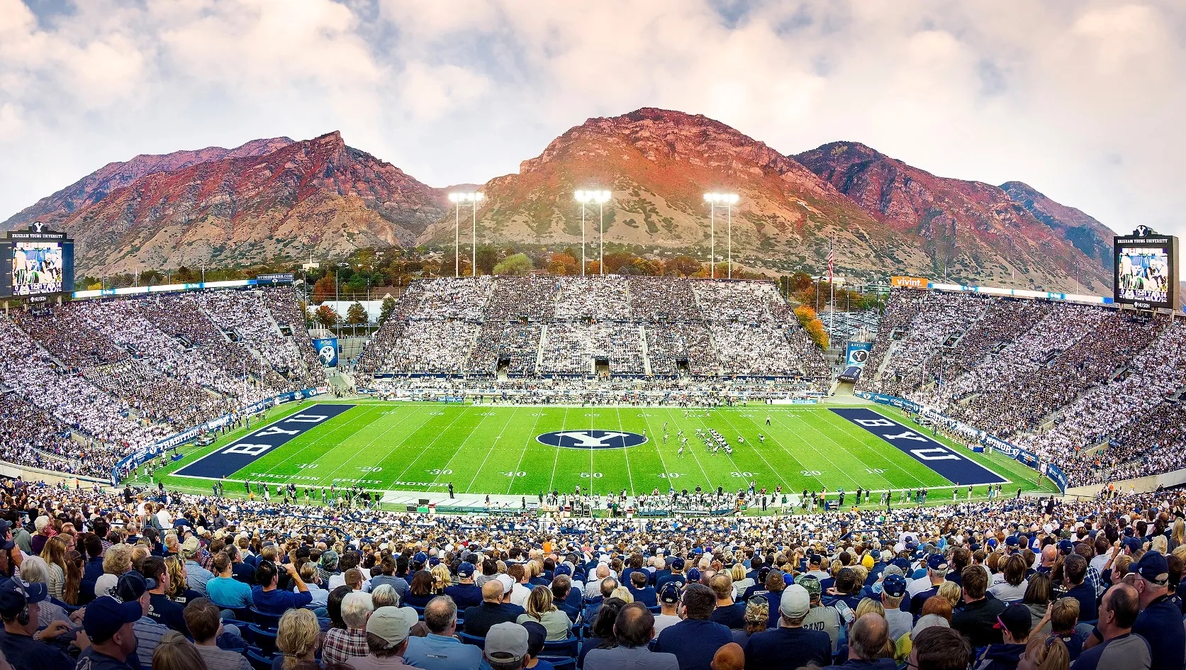 A full college football stadium beneath the mountains